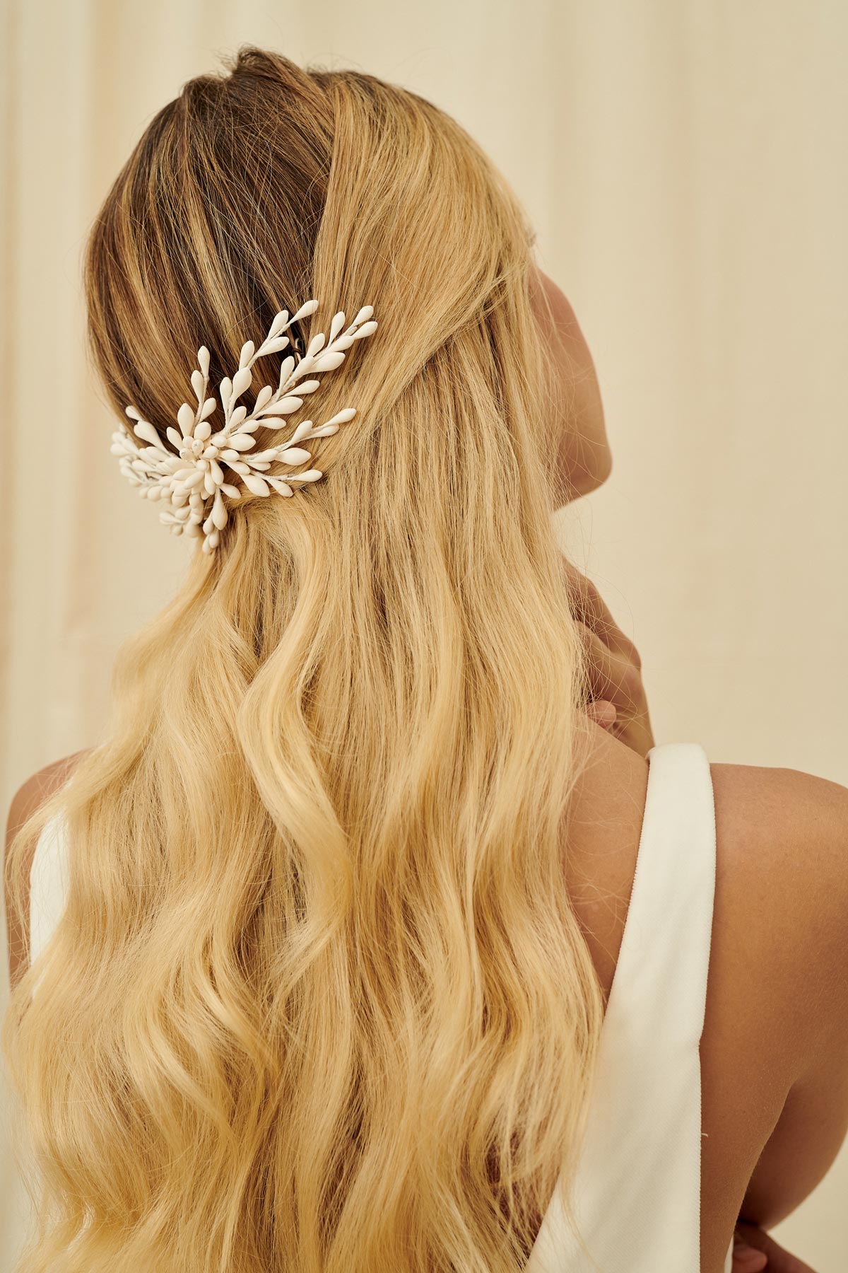 A delicate bridal hair accessory made from wax orange blossoms set into a comb