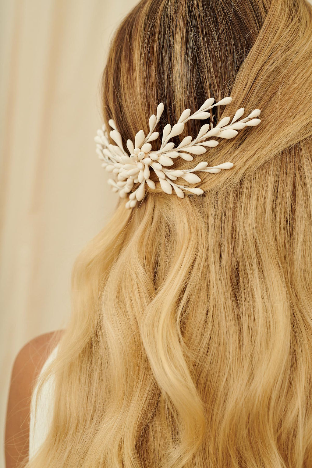 A delicate bridal hair accessory made from wax orange blossoms set into a comb