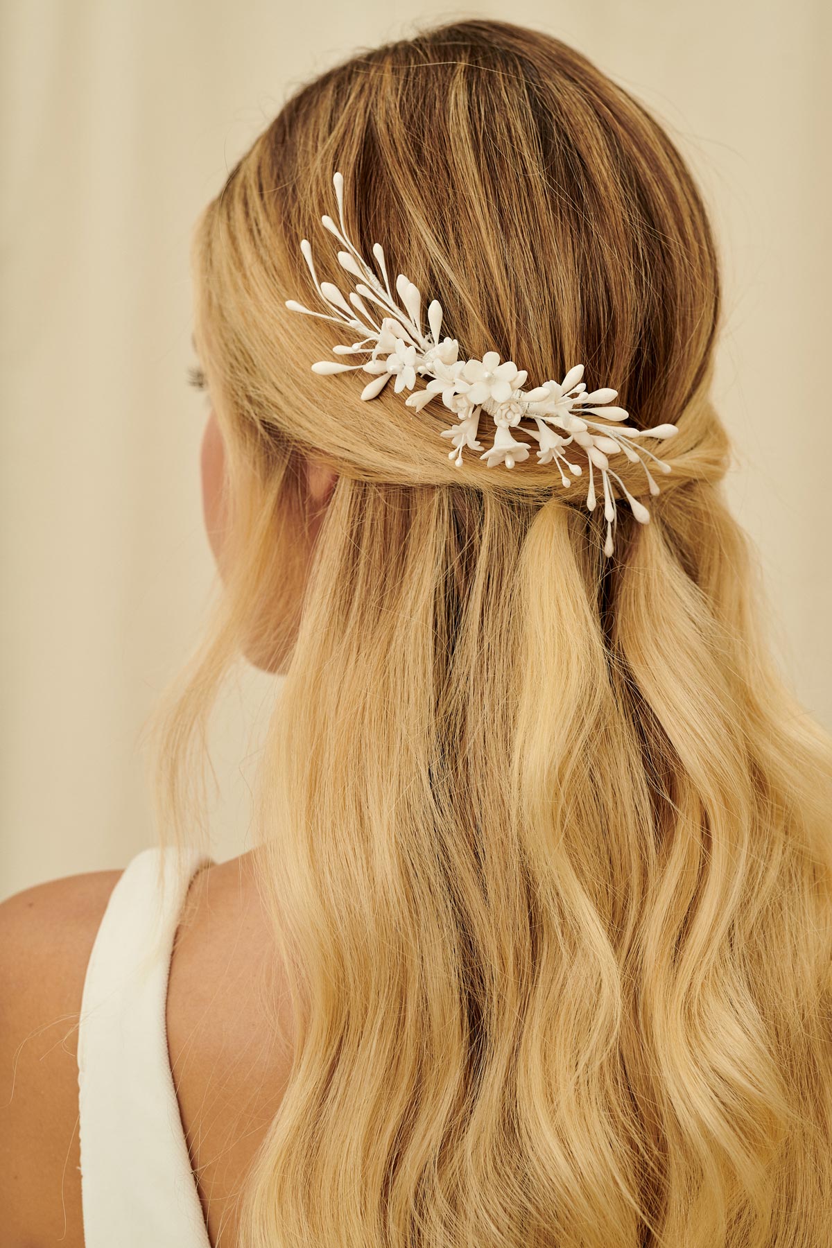 An asymmetrical bridal hair comb wired with wax orange blossoms and porcelain flowers