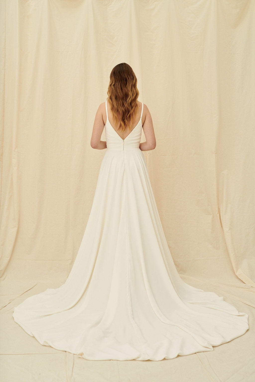 Super low cut crepe wedding dress with spaghetti straps, pockets, and a huge train
