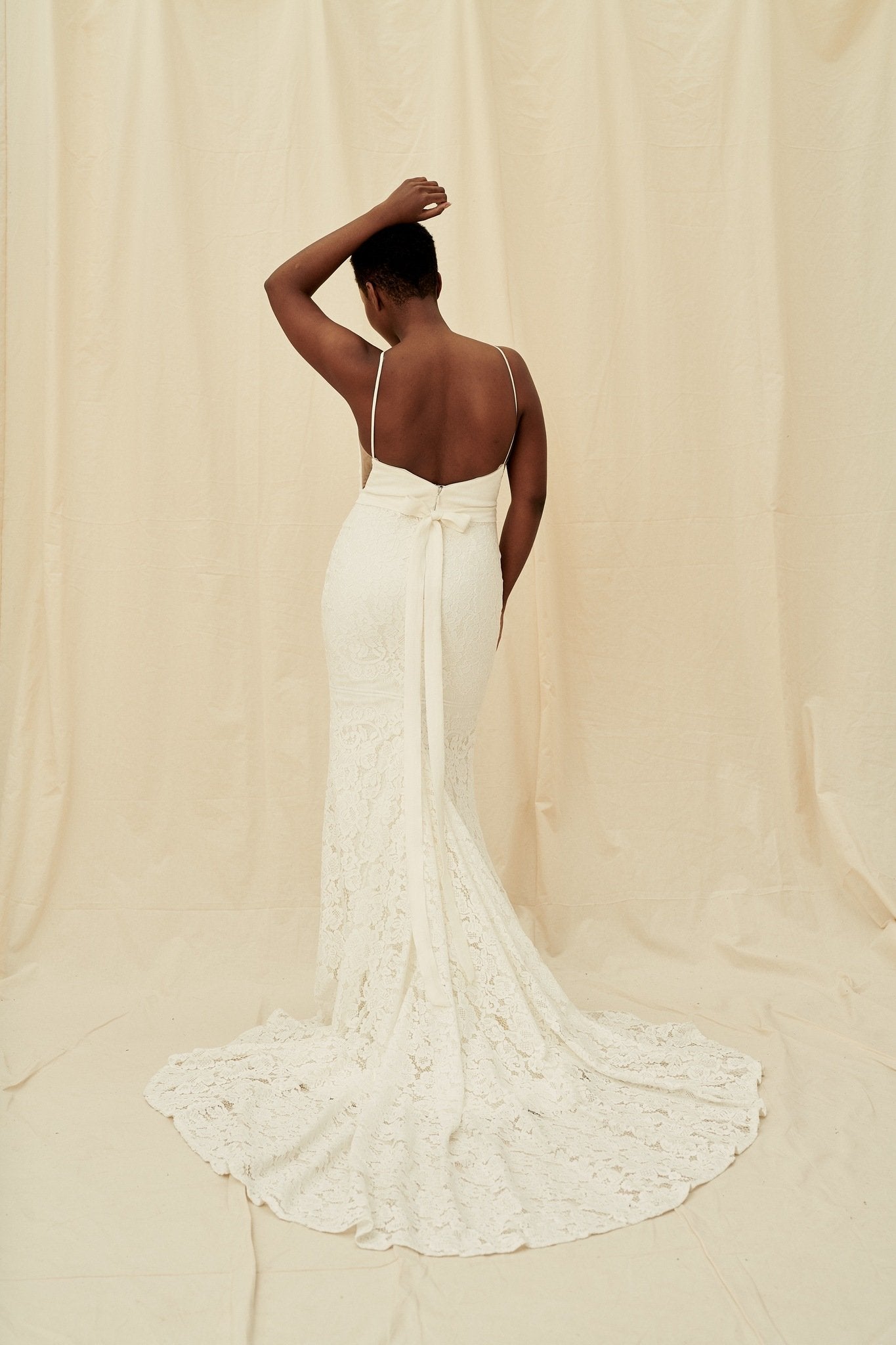 A fitted, high-neck crepe lace gown with a hidden leg slit and a built-in bow