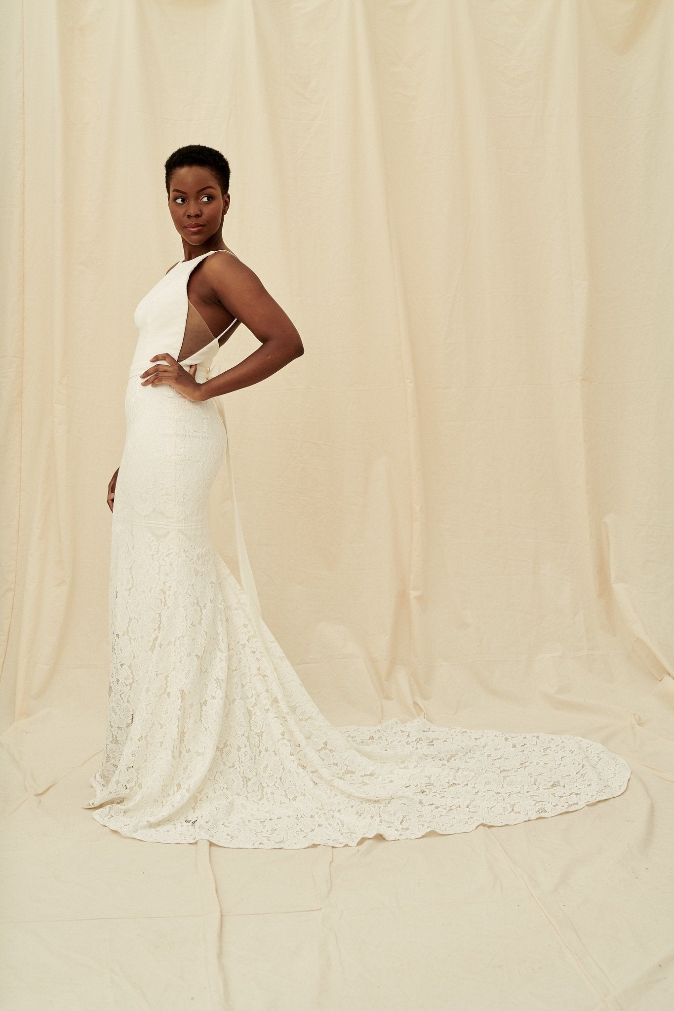 A fitted, high-neck crepe lace gown with a hidden leg slit and a built-in bow
