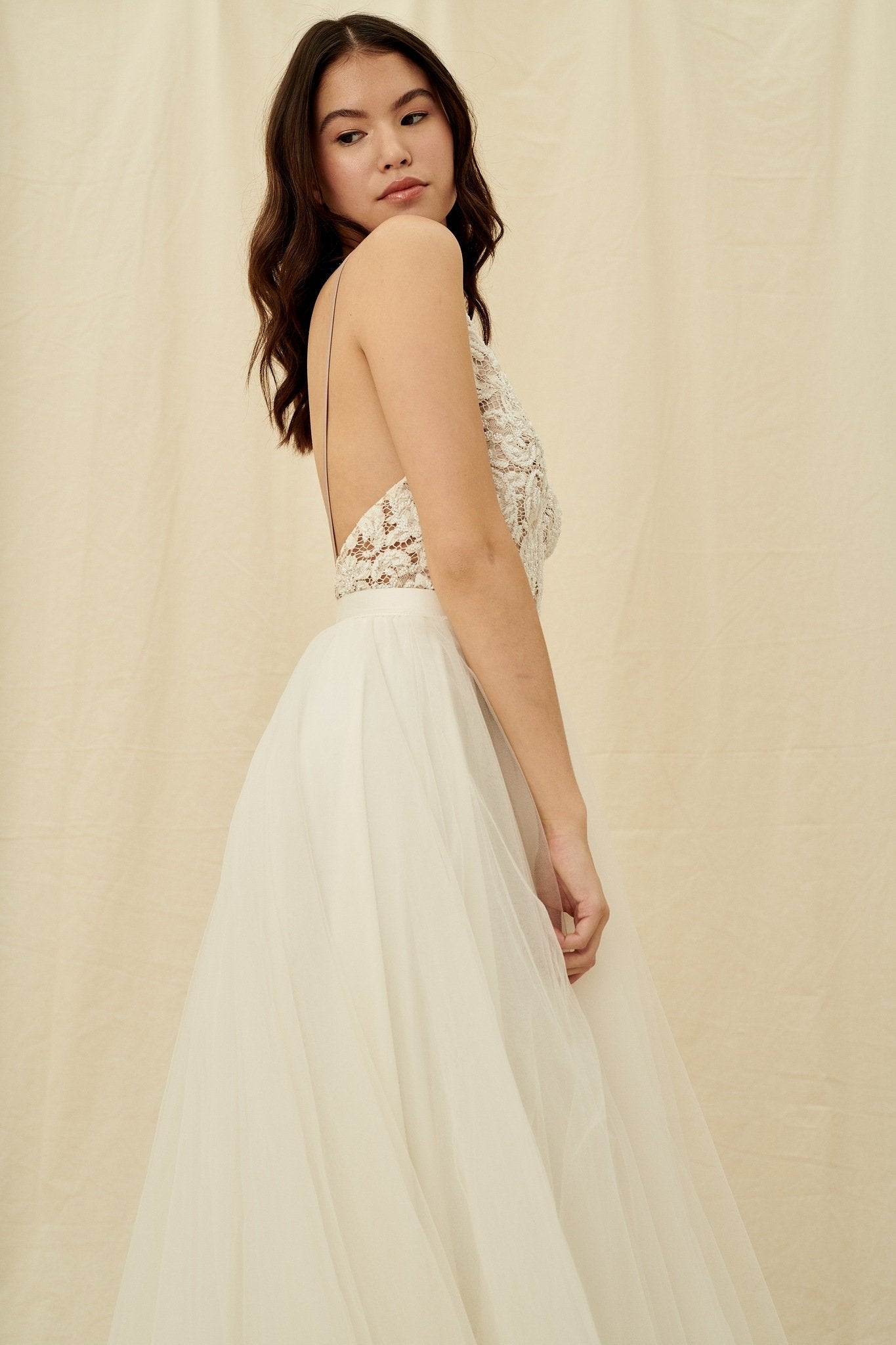 A princess wedding gown with a beaded bodice, open back, and tulle skirt with a train by Truvelle