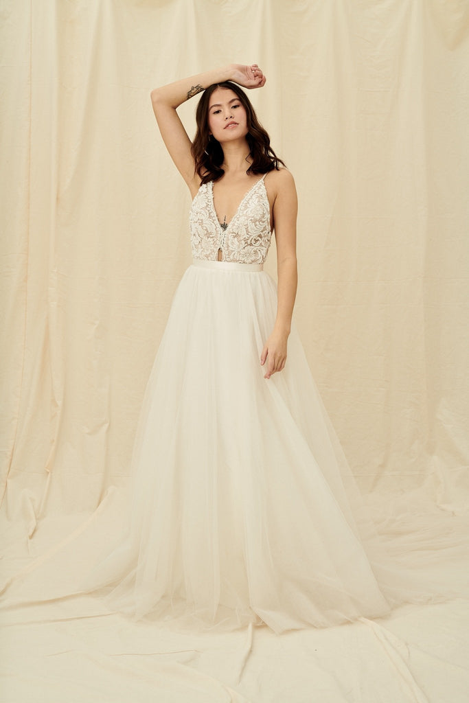 A princess wedding gown with a beaded bodice, open back, and tulle skirt with a train
